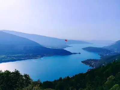 a red parachute flying over a large body of water at La Tanière des Cimes, sauna privé in Passy