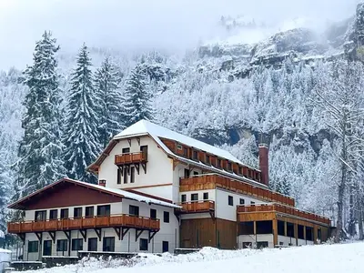 a building covered in snow with a mountain in the background at La Tanière des Cimes, sauna privé in Passy