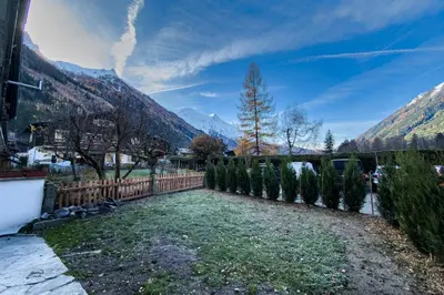 a fence with trees and mountains in the background at Apartment with garden and proximity to activities in Chamonix-Mont-Blanc