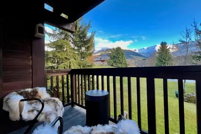 a couple of dogs sitting on a porch looking at a view at Bright apartment with balcony and pool in Megève