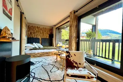 a room with a balcony with a bed and a television at Bright apartment with balcony and pool in Megève