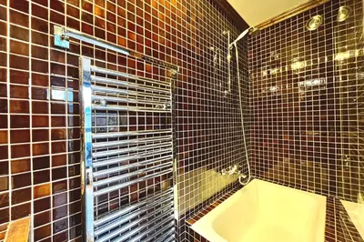 a bathroom with black tiled walls and a tub at Bright apartment with balcony and pool in Megève