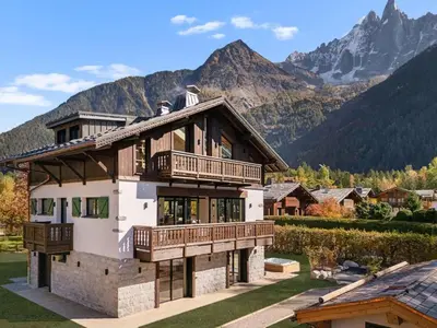 a large house with mountains in the background at Chalet Larzay - Chamonix in Chamonix-Mont-Blanc