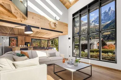 a living room with a white couch and large windows at Chalet Larzay - Chamonix in Chamonix-Mont-Blanc