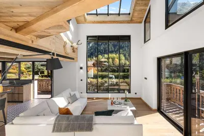 a living room with white furniture and large windows at Chalet Larzay - Chamonix in Chamonix-Mont-Blanc
