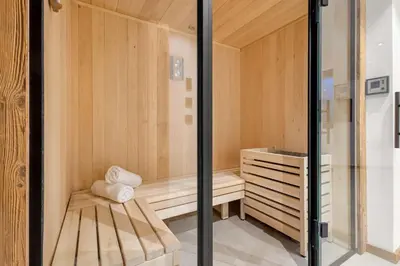 a wooden sauna with a wooden bench and a stool at Chalet Larzay - Chamonix in Chamonix-Mont-Blanc