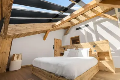 a bedroom with a large wooden bed with white sheets at Chalet Larzay - Chamonix in Chamonix-Mont-Blanc