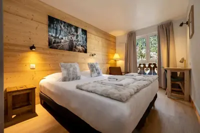 a bedroom with a large white bed with wooden walls at Cozy Sleeps 4 Mountain view 300m lift in Chamonix-Mont-Blanc