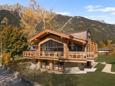 a large wooden house with mountains in the background at Chalet Rémond - Vue Montagnes in Chamonix-Mont-Blanc