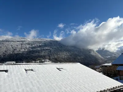 a snow covered roof with a mountain in the background at Triplex de 42m2 proche piste retour de St-Gervais in Saint-Gervais-les-Bains