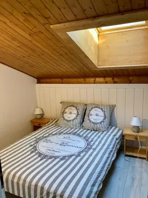 a bed with a blue and white striped comforter in a room at Triplex de 42m2 proche piste retour de St-Gervais in Saint-Gervais-les-Bains
