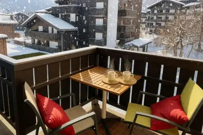 a table and chairs on a balcony with snow at Bright apartment in the heart of Chamonix in Chamonix-Mont-Blanc