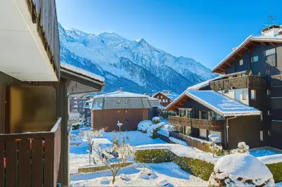 a snow covered city with mountains in the background at Bright apartment in the heart of Chamonix in Chamonix-Mont-Blanc