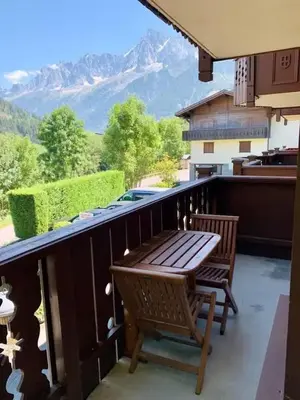 a patio with a wooden table and chairs on a balcony at Les Grands Tetras in Les Houches