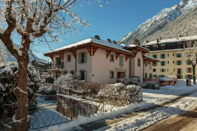 a house in the snow in front of a mountain at Les Sonnailles Apartment - Chamonix All Year in Chamonix-Mont-Blanc