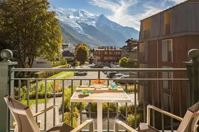 a balcony with a table and chairs and a mountain at Les Sonnailles Apartment - Chamonix All Year in Chamonix-Mont-Blanc