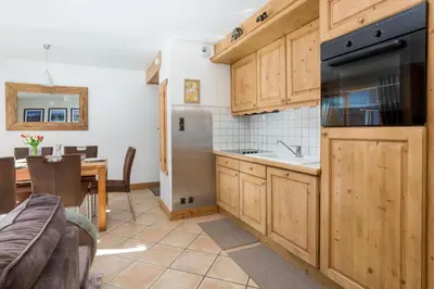 a kitchen with wooden cabinets and a stainless steel refrigerator at Les Sonnailles Apartment - Chamonix All Year in Chamonix-Mont-Blanc