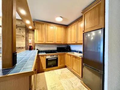 a kitchen with wooden cabinets and a stainless steel refrigerator at The Balcony of the Giant in Combloux in Combloux