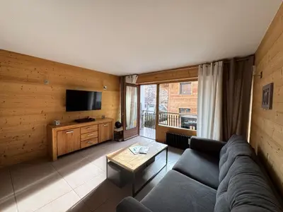 a living room with a couch and a television at Studio cabine cosy Megève parking gratuit in Megève