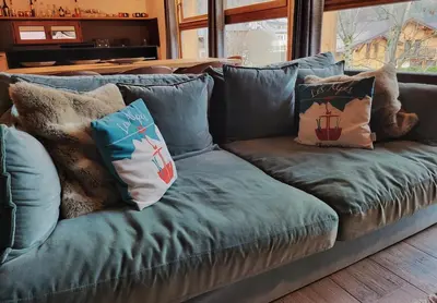 a blue couch with pillows on it in a living room at Maison du Tailleur de Pierre, 5 bedroom apartment, 3 bathrooms, ski-bus, parking in Samoëns