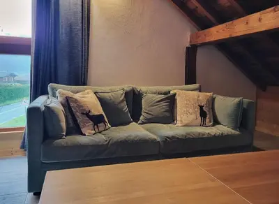 a couch with pillows on it in a room with a window at Maison du Tailleur de Pierre, 5 bedroom apartment, 3 bathrooms, ski-bus, parking in Samoëns