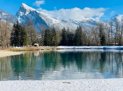 a lake with a snow covered mountain in the background at Maison du Tailleur de Pierre, 5 bedroom apartment, 3 bathrooms, ski-bus, parking in Samoëns
