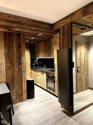 a kitchen with wooden walls and a refrigerator at Appartement cosy proche du centre de Megève in Megève