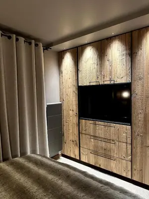 a bedroom with a television and a wall of wood panels at Appartement cosy proche du centre de Megève in Megève