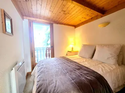 a bedroom with a large bed with a large window at Charming sunny duplex in Megève