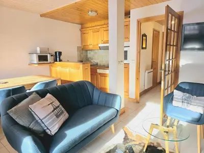 a living room with a blue couch and a kitchen at Charming sunny duplex in Megève