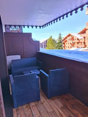 a patio with two chairs and a table on a balcony at CoconAlpin au coeur de la station in Arâches-la-Frasse