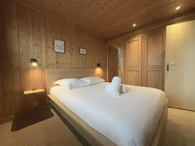 a bedroom with a large white bed with wooden walls at Le Grison in Megève