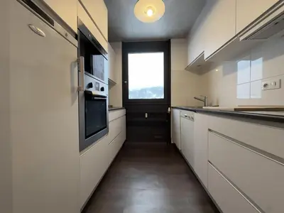 a kitchen with white cabinets and a window at Le Grison in Megève