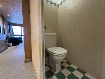 a bathroom with a toilet and a checkered floor at Le Grison in Megève