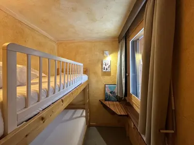 a small bedroom with a bunk bed and a window at Le Grison in Megève