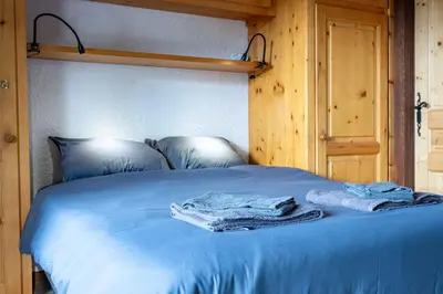 a bed with blue sheets and two towels on it at 1BDR 4P apartment with balcony and parking- Megève in Megève