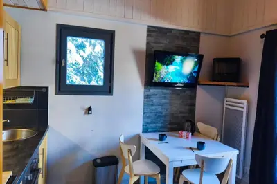 a small kitchen with a white table and a tv on the wall at Charming apartment with mezzanine in the mountain in Demi-Quartier
