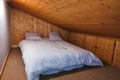 a bed in a room with a wooden ceiling at Charming apartment with mezzanine in the mountain in Demi-Quartier
