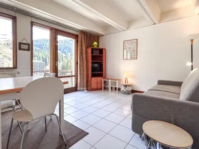 a living room with a couch and a table at Grand studio Flaine Forum vue montagne in Flaine
