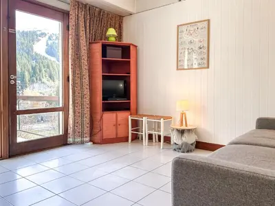 a living room with a couch and a tv and a window at Grand studio Flaine Forum vue montagne in Flaine