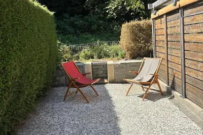 two chairs sitting on a patio next to a hedge at La Kabane d'Orsin 3 étoiles in Saint-Gervais-les-Bains