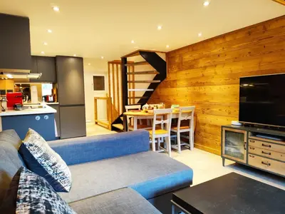 a living room with a blue couch and a kitchen at La Kabane d'Orsin 3 étoiles in Saint-Gervais-les-Bains
