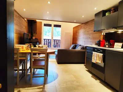 a kitchen and living room with a table and a couch at La Kabane d'Orsin 3 étoiles in Saint-Gervais-les-Bains