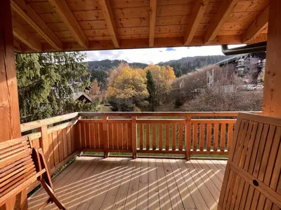 a large wooden porch with a bench on a deck at Duplex neuf 78m², 2 chambres, poêle, WIFI, parking, pour 5 pers. - Arâches-la-Frasse - FR-1-836-57 in Arâches-la-Frasse