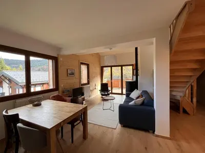a living room with a table and a blue couch at Duplex neuf 78m², 2 chambres, poêle, WIFI, parking, pour 5 pers. - Arâches-la-Frasse - FR-1-836-57 in Arâches-la-Frasse