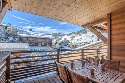 a wooden balcony with a table and chairs on it at Appartement Pravy - Welkeys in Megève