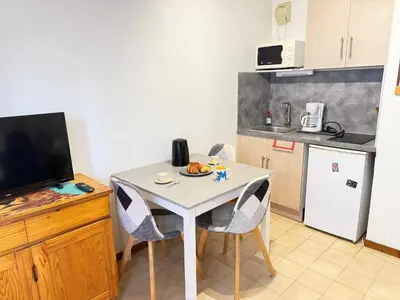 a small kitchen with a table with chairs and a kitchen at L'Orée du Parc in Saint-Gervais-les-Bains