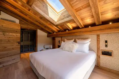 a bedroom with a white bed with a wooden ceiling at Chalet Les Sapins - Megève in Megève