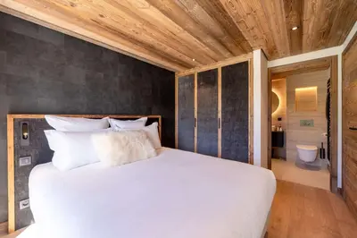 a bedroom with a large white bed and a bathroom at Chalet Les Sapins - Megève in Megève