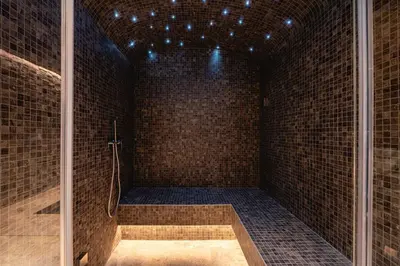 a bathroom with a walk in shower in a brick wall at Chalet Les Sapins - Megève in Megève